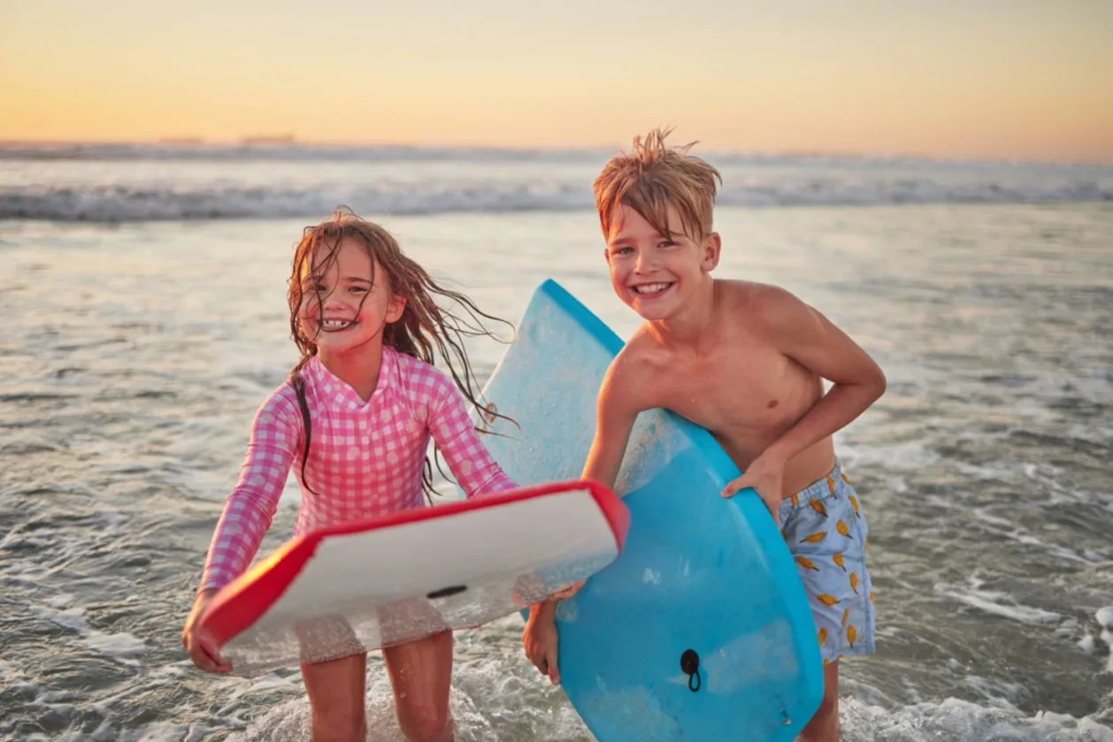 Siblings at beach with boogie boards — family-friend travel destination San Diego